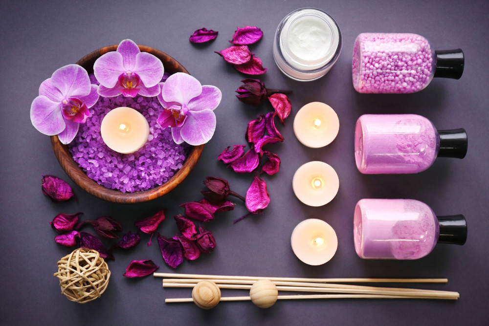 Composizione aromaterapeutica con orchidee viola, candele accese, sale e oli essenziali