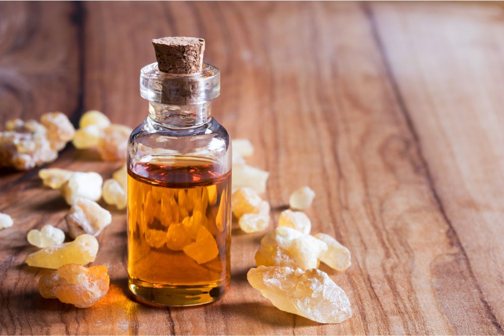 Olio essenziale di incenso in un flaconcino con grani di incenso su una base di legno