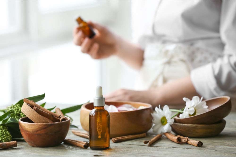 Flaconcini di vetro con oli essenziali circondati da erbe fresche e fiori