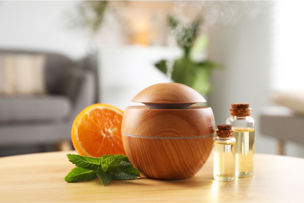 Aromadiffusore in legno con oli essenziali, menta e arancia in un accogliente interno domestico.