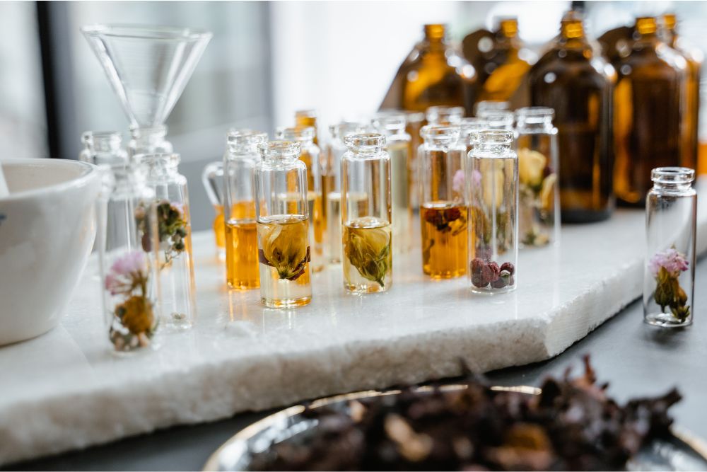 Bicchierini con vari oli essenziali di erbe ed erbe fresche su un supporto di legno – aromaterapia naturale
