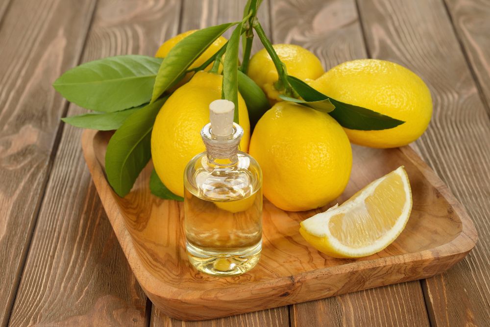 Olio di limone in un piccolo flaconcino con limoni freschi su una base di legno