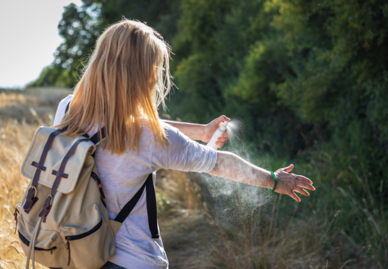 Donna all'aperto che usa uno spray naturale contro le zanzare
