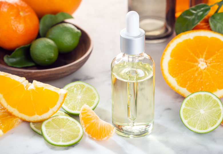 Flaconcino con olio essenziale di limone tra fette fresche di agrumi – un prodotto naturale per pulire senza chimica.