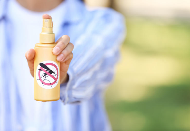 Persona che tiene uno spray repellente contro le zanzare all'aperto.